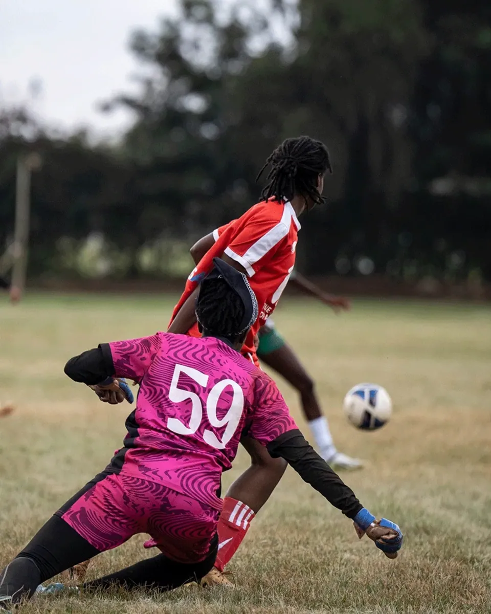 A goalkeeper diving full stretch across her line
