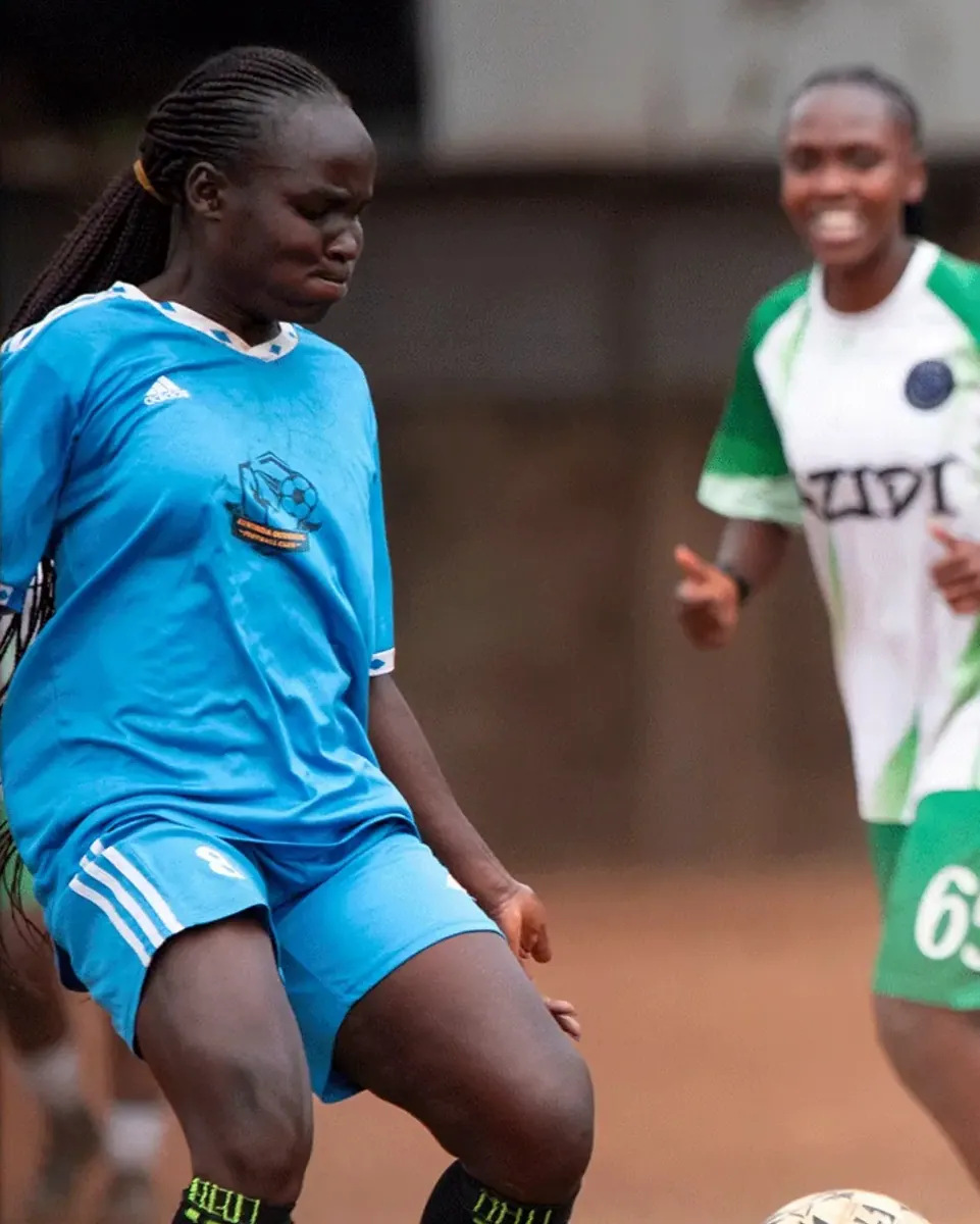 Two players competing for the ball on a dirt pitch